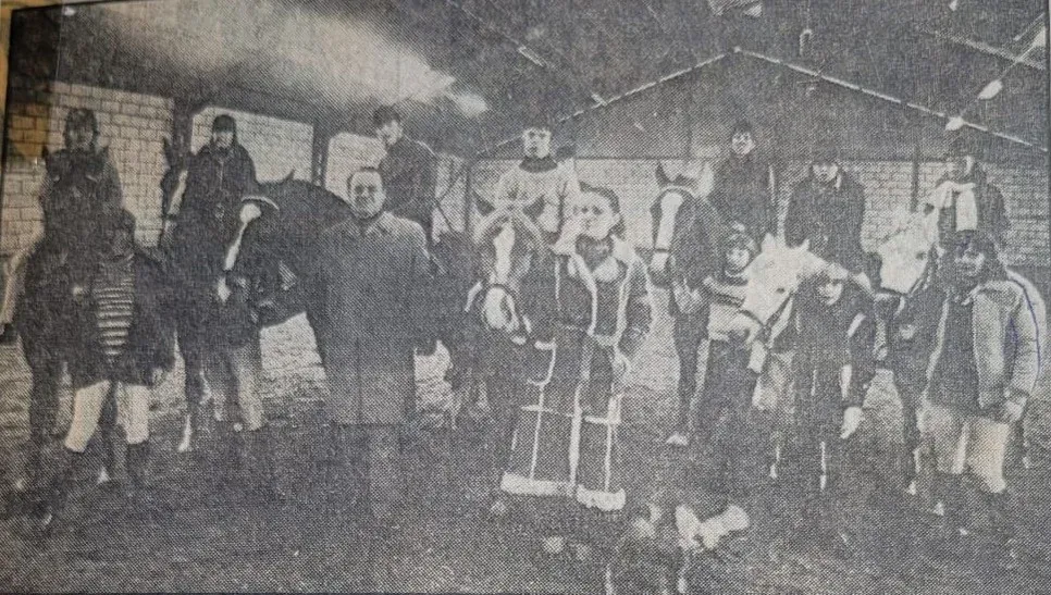 Zwart-witfoto uit 1979: ruiters te paard met vrijwilligers ernaast, opgesteld in de binnenbak van de Legmeermanege.